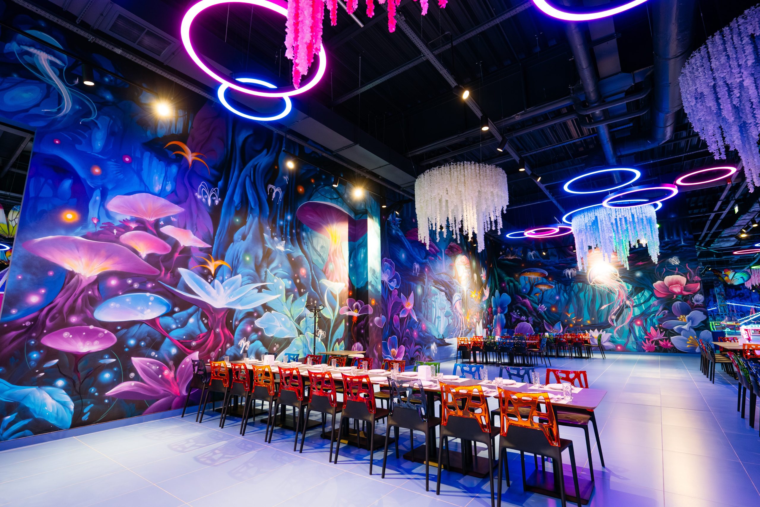 Panoramic view of 1500 square meter fantasy interior mural with hanging jellyfish installations and neon lighting creating immersive restaurant atmosphere