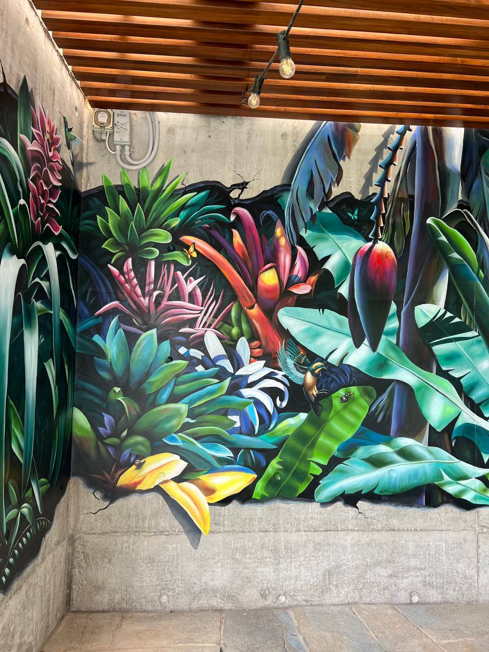 Full view of 3D tropical mural showing wall breach illusion effect with exotic plants and flowers