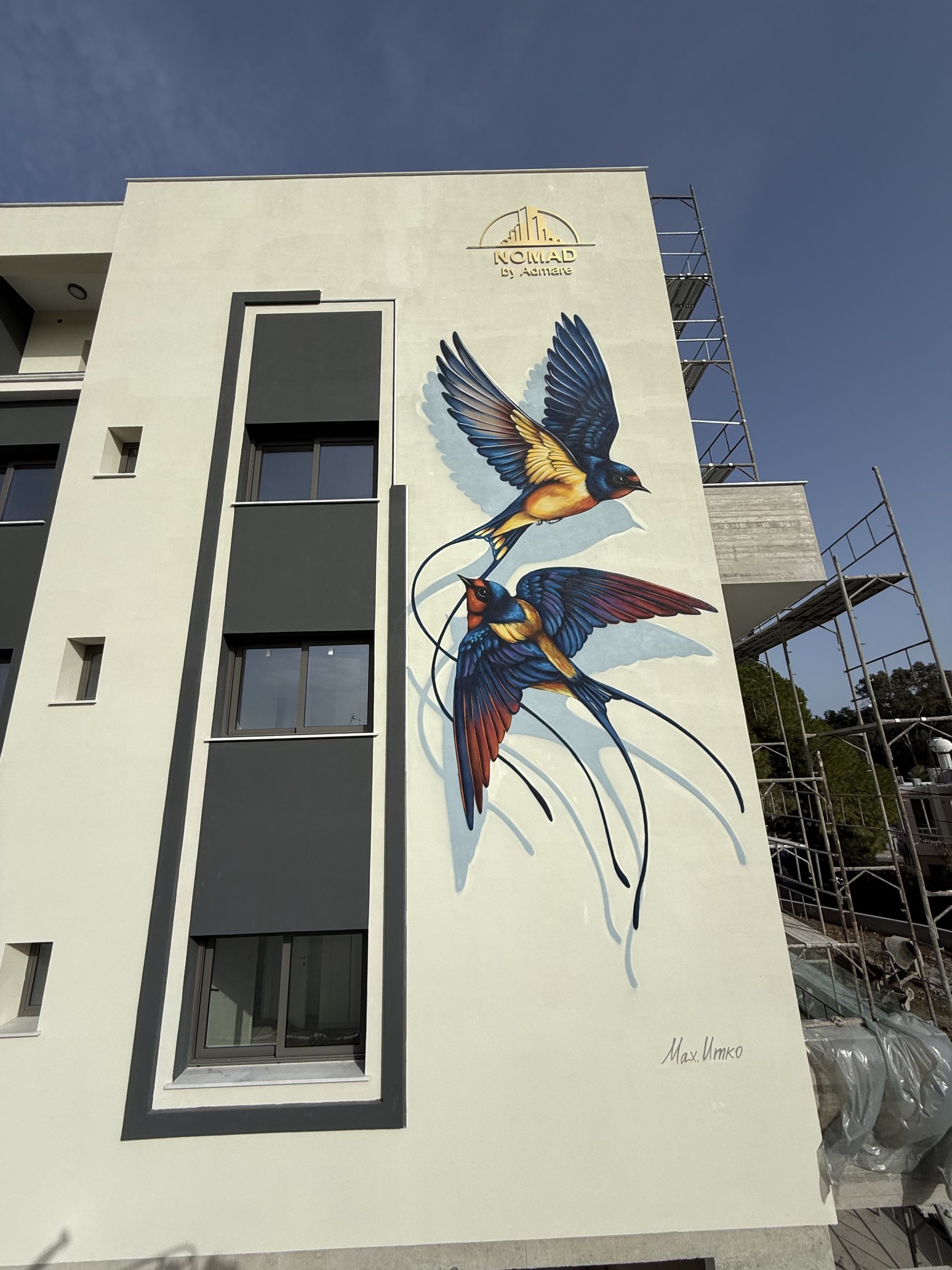 Modern residential building exterior featuring 40 square meter mural of flying swallows in blue and ochre colors