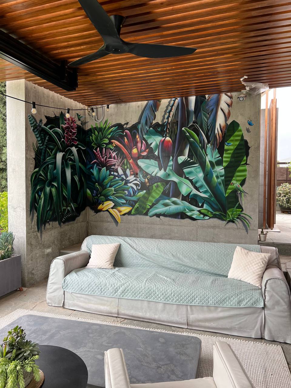 Tropical hyperrealistic mural on covered patio with wooden slat ceiling and modern outdoor seating