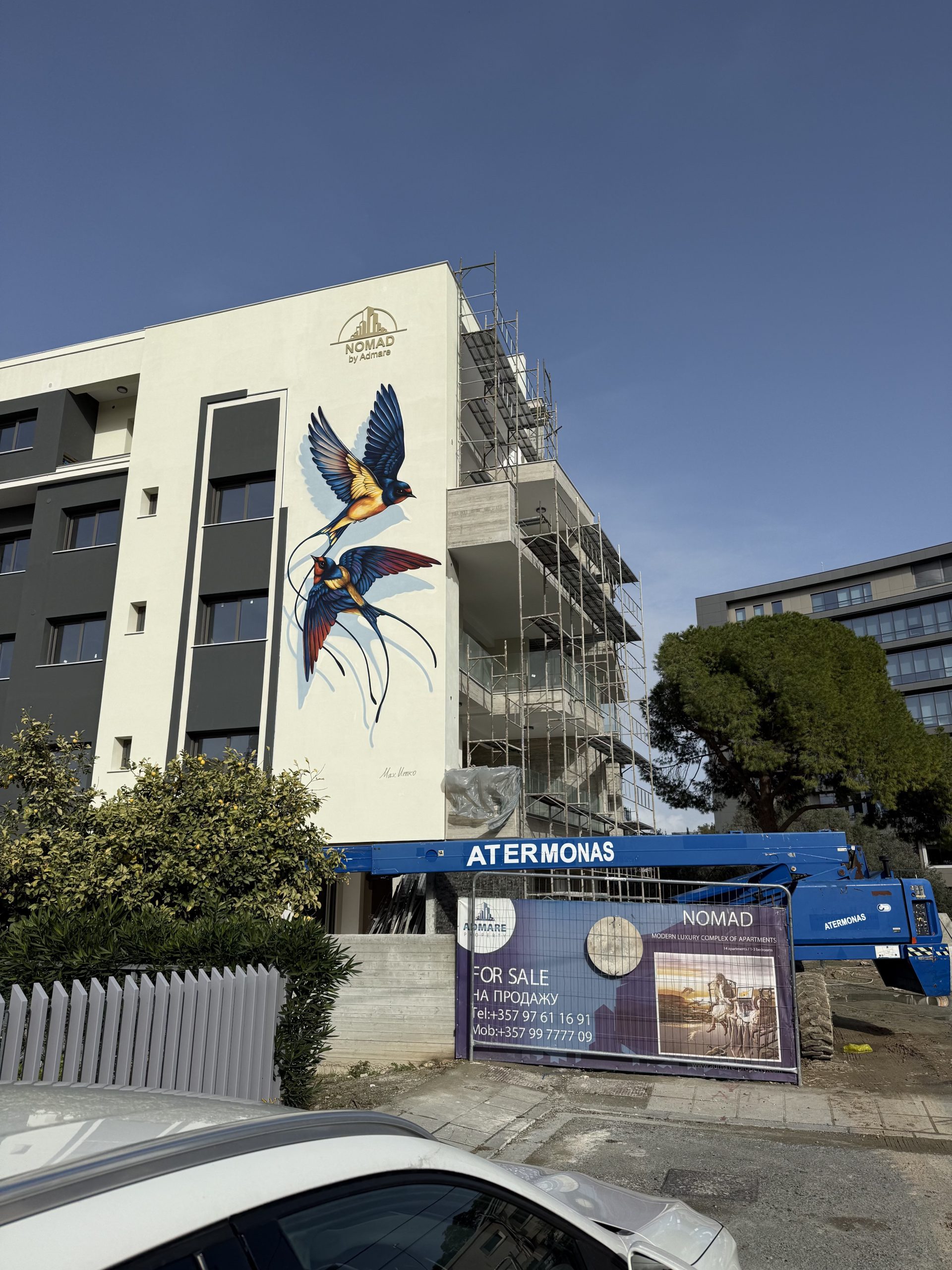 Aerial view of NOMAD residential complex with large-scale swallow mural on building facade in Paphos Cyprus
