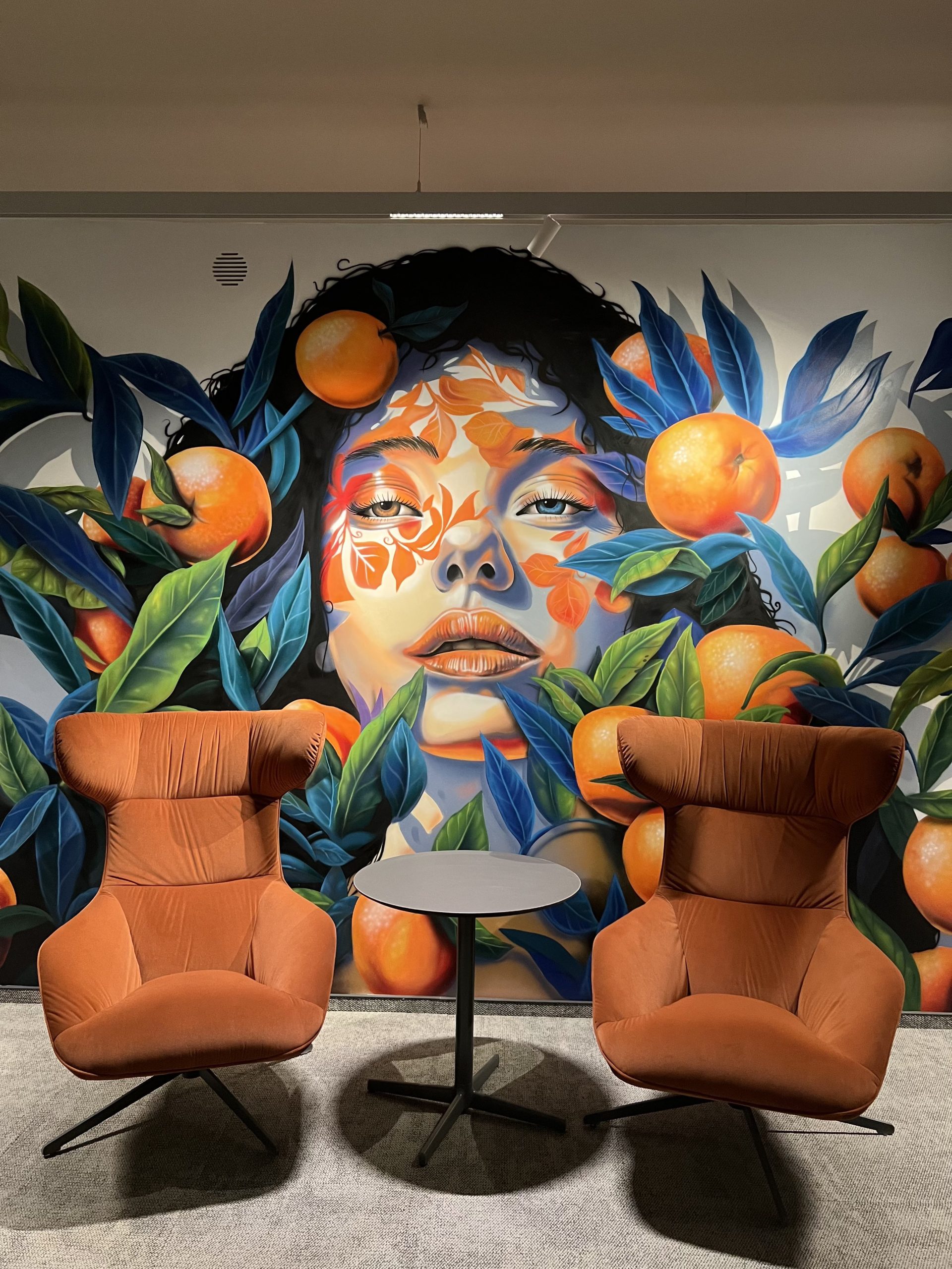 Detailed view of airbrushed office mural with botanical elements and portrait in modern workspace interior