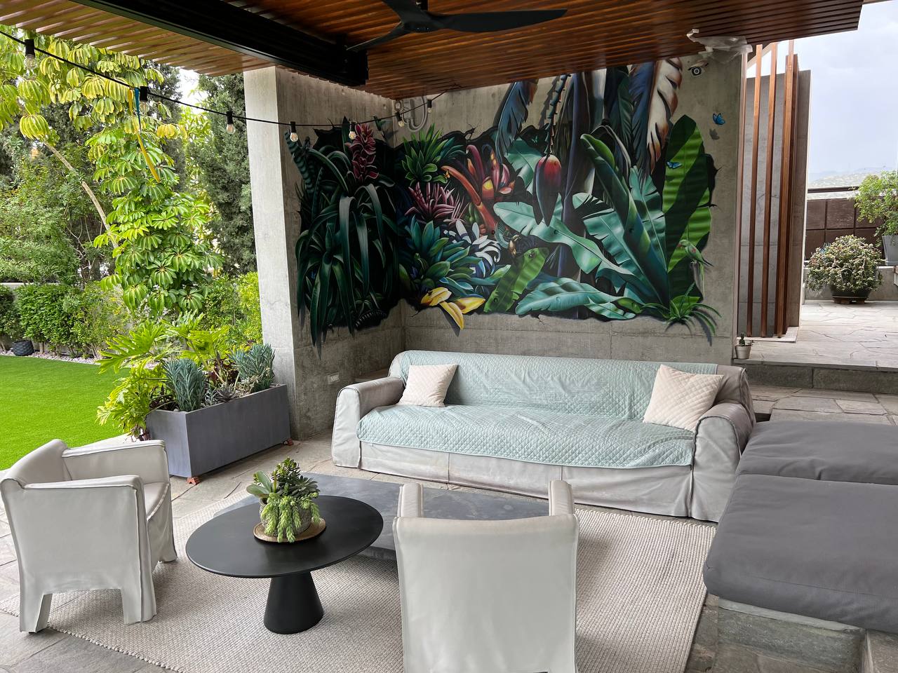 Outdoor terrace living area featuring large-scale tropical mural with garden views and contemporary furniture