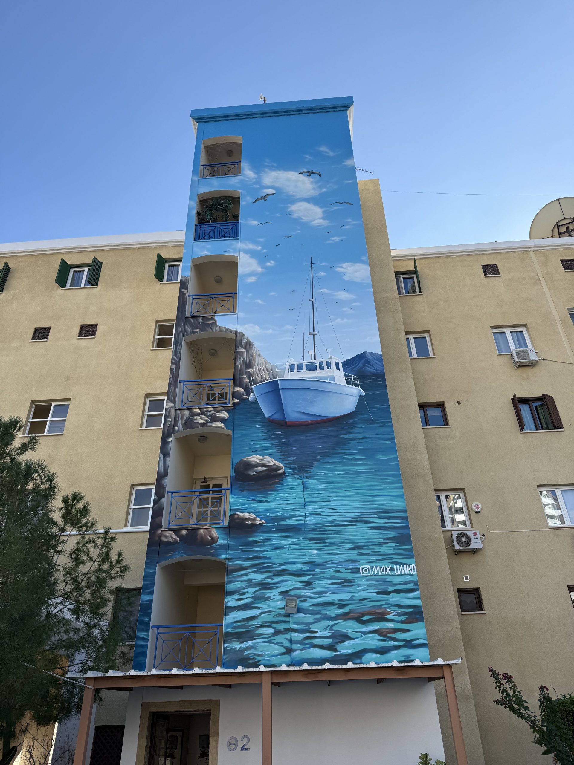 Building facade mural showing boat on water with seabirds and coastal landscape