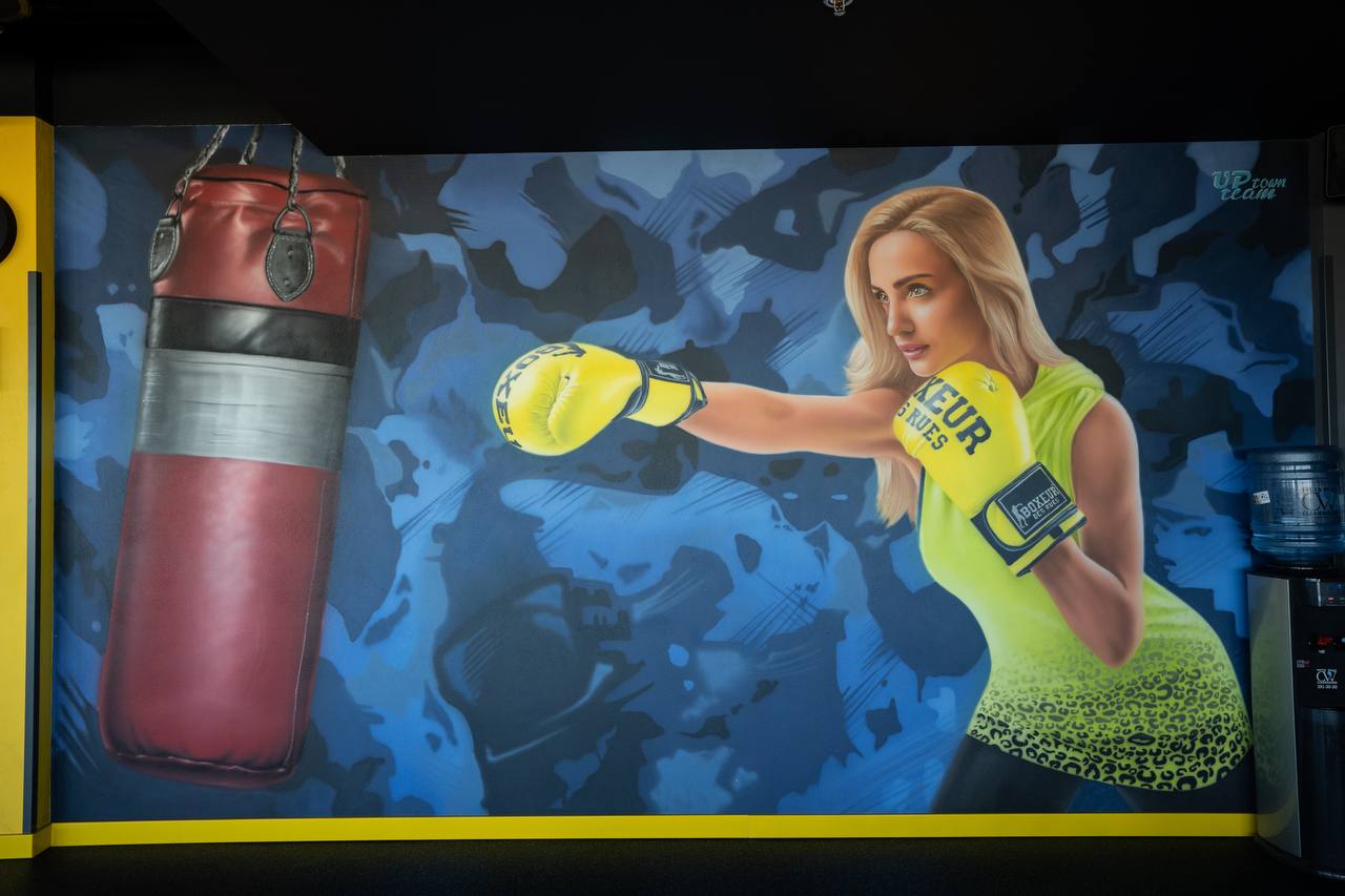 Large-scale interior gym mural featuring female athlete with boxing gloves and punching bag
