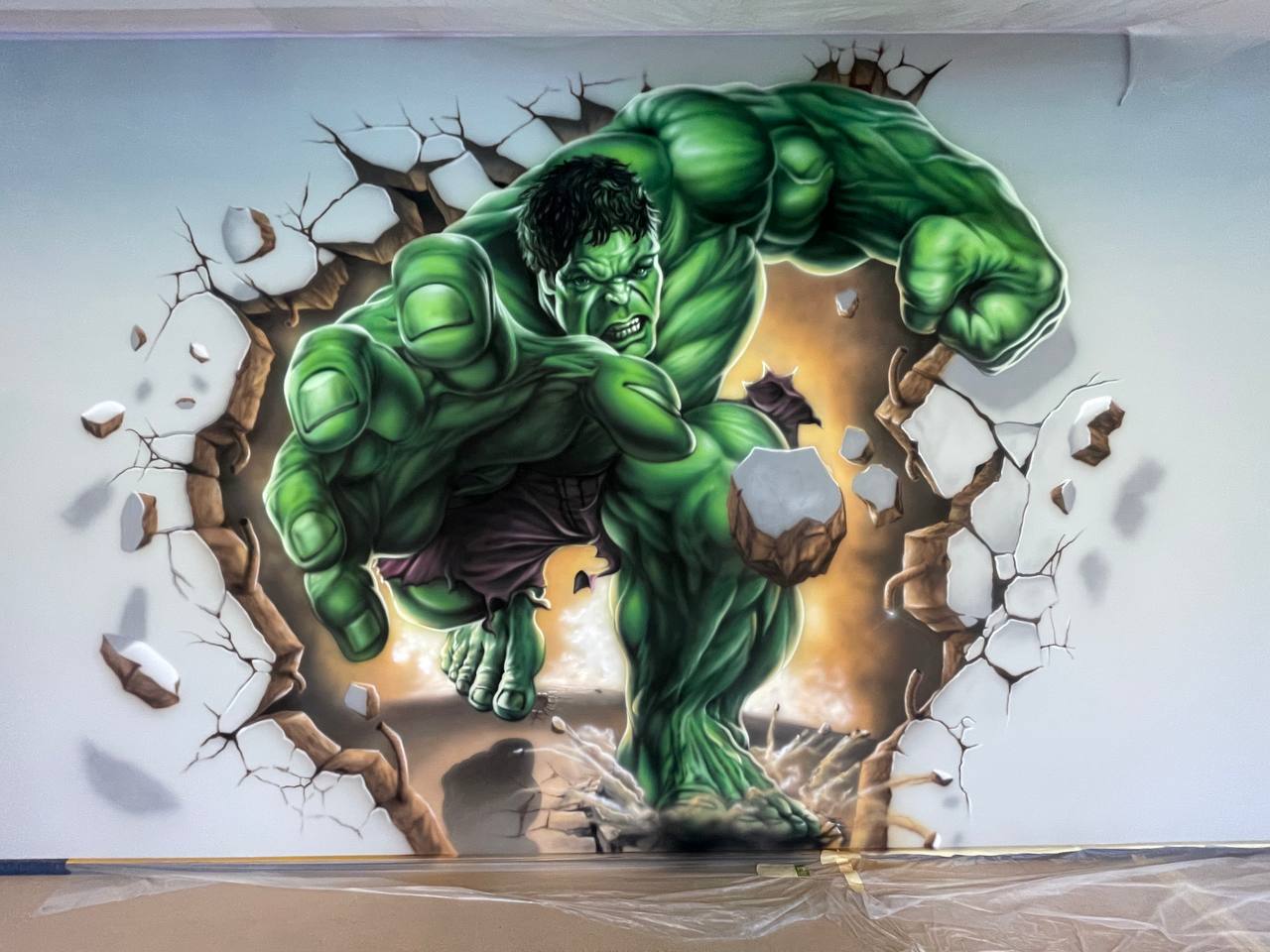Interior wall painting featuring 3D superhero breaking through surface with dramatic lighting effects