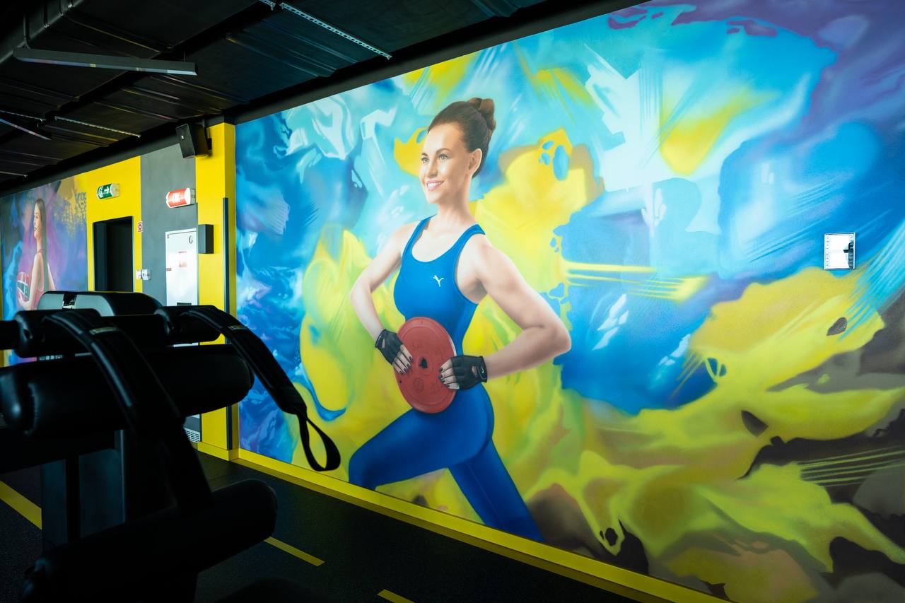 Corporate gym interior mural showing fitness athlete with weight plate on vibrant blue and yellow background