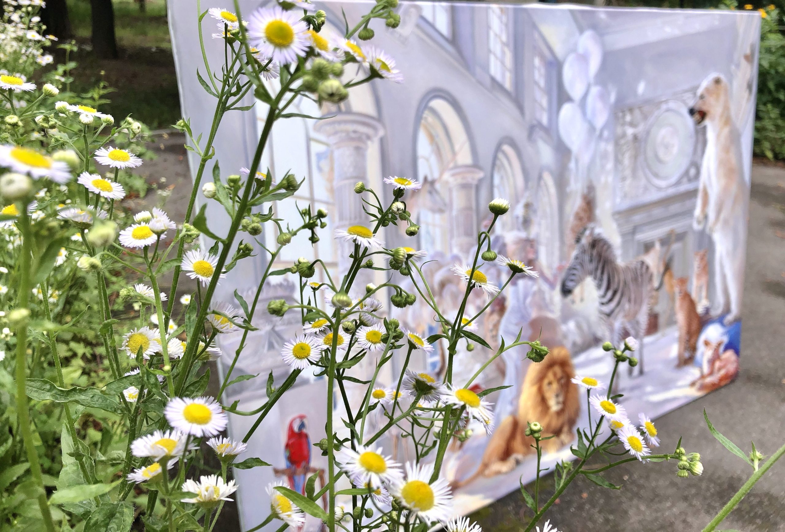 Custom oil painting canvas displayed in garden setting showing wildlife palace composition with lion and tropical birds