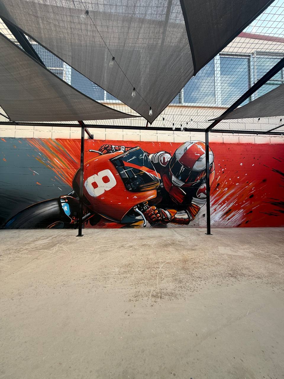 Motorcycle racing themed mural adjacent to cafe seating area at track venue