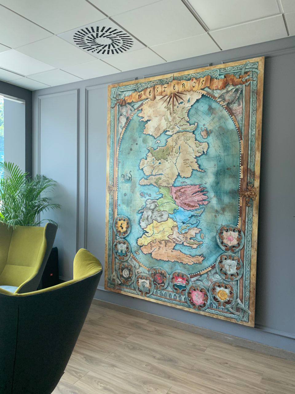 Large-scale hand-painted Westeros fantasy map canvas displayed in modern office interior